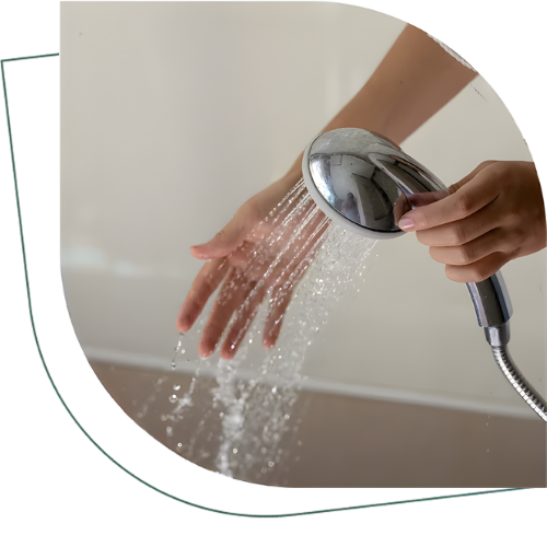 Hand holding glass under running faucet representing hot water service by Polly Plumbing in Keller Texas