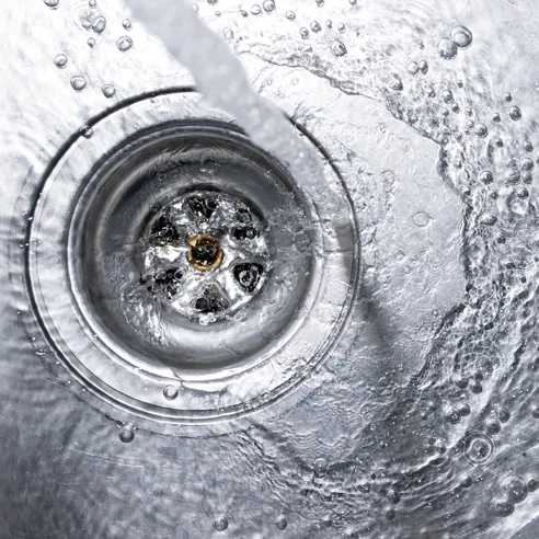 Clogged kitchen sink drain being cleared with running water in Keller TX residence